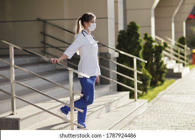 Female Doctor Or Nurse In A Protective Face Mask Walking Up The Stairs