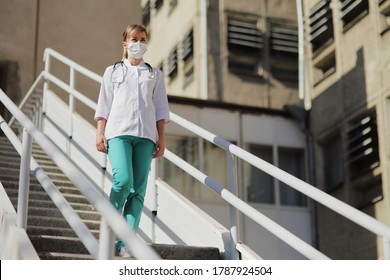 Female Doctor Or Nurse In A Protective Face Mask Walking Up The Stairs