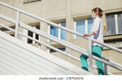 Female Doctor Or Nurse In A Protective Face Mask Walking Up The Stairs