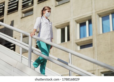 Female Doctor Or Nurse In A Protective Face Mask Walking Up The Stairs