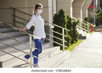 Female Doctor Or Nurse In A Protective Face Mask Walking Up The Stairs