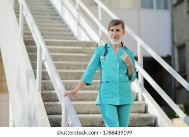 Female Doctor Or Nurse In A Protective Face Mask Walking Up The Stairs