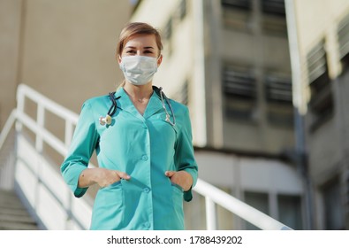 Female Doctor Or Nurse In A Protective Face Mask Walking Up The Stairs