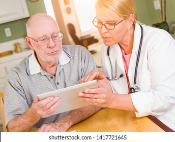 Female Doctor Or Nurse Showing Senior Man Touch Pad Computer At Home.