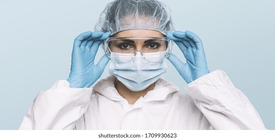 Female Doctor or Nurse Wearing latex protective gloves and medical Protective Mask and glasses on face. Protection for Coronavirus COVID-19 - Powered by Shutterstock