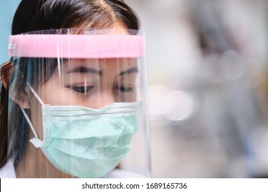 female doctor nurse wearing protective gear of surgical mask and face shield, protection against contagious corona virus disease COVID-19, health care worker in hospital diagnosing patients 