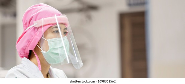 Female Doctor Nurse Wearing Protective Gear Of Surgical Mask And Face Shield For Safety, Protection Against Contagious Corona Virus Disease COVID-19, Health Care Worker In Hospital Diagnosing Patients