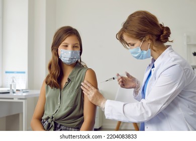 Female Doctor Or Nurse In White Coat Giving Arm Injection To Child. Happy Teenage School Girl In Facemask Getting Flu, Covid 19 Or Monkeypox Vaccine During Mass Vaccination And Immunization Campaign