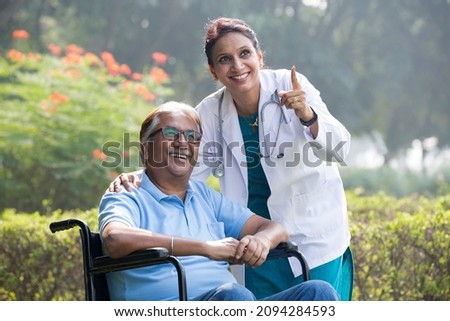 Female doctor with old man in wheelchair admiring view at park
