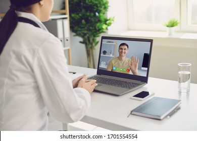 Female Doctor Online. Doctor Speaks With A Patient Using A Laptop Sitting Behind A Straw In A Clinic Office. Online Medical Consultation.