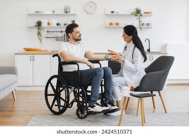 Female doctor and patient with disability having talk about diagnosis and medical checkup in modern kitchen. Attentive man with electronic display on hand listening attentively to female physician. - Powered by Shutterstock