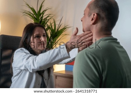 Female doctor performing thyroid function examination on male patient during medical checkup in clinic office	