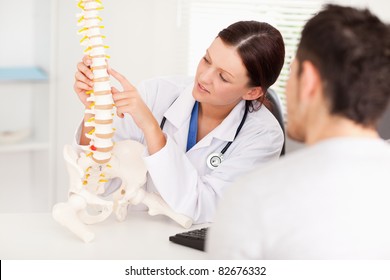 A female doctor is pointing on a bone in the spine - Powered by Shutterstock