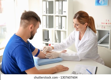 Female Doctor Preparing Patient For Blood Draw In Clinic