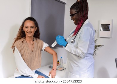 Female doctor preparing syringe for vaccinating smiling female patient in medical office - Powered by Shutterstock