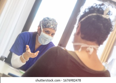 Female doctor with protective mask speaks with a patient wearing a mask to prevent infection. Sitting into studio. Healthcare trust concept.