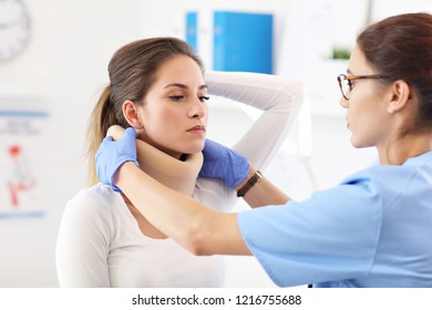 Female Doctor Putting Neck Orthopaedic Collar On Adult Injured Woman