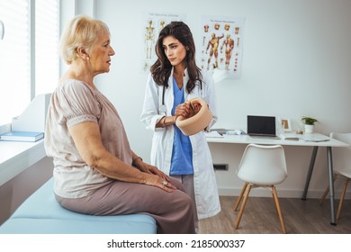 Female Doctor Putting Neck Orthopaedic Collar On Adult Injured Woman. Picture Of Senior Woman Having A Visit At Female Doctor's Office. Doctor Helping A Senior Woman With Her Neck Injury