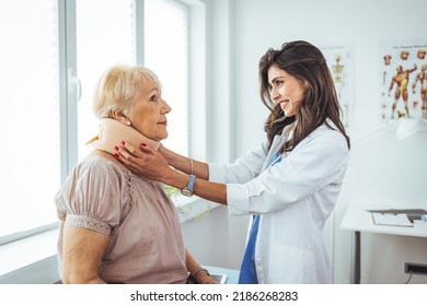 Female Doctor Putting Neck Orthopaedic Collar On Adult Injured Woman. Doctor Talking To A Senior Patient With Cervical Collar At The Hospital. Doctor Applying Cervical Collar On Neck Of Woman