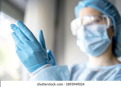 A Female Doctor Putting On Protective Blue Gloves