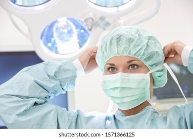 Female doctor putting on surgical mask in operating room