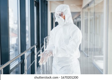 Female Doctor Scientist In Lab Coat, Defensive Eyewear And Mask Standing Indoors And Wearing Gloves.