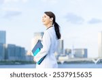 A female doctor or scientist in a white lab coat standing with a city in the background