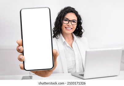 Female Doctor Showing Big Smartphone With Blank Screen, Sitting In Office At Workplace, Closeup, Mockup. Professional Physician Advertising Medical Mobile Application Or Website