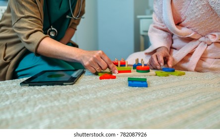 Female Doctor Showing Geometric Shape Game To Elderly Female Patient With Dementia