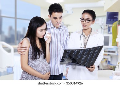 Female doctor showing x-ray results to young couple in clinic - Powered by Shutterstock