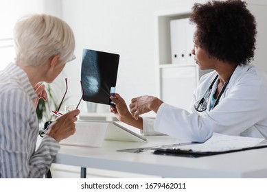 A Female Doctor Sits At Her Desk And Talks To A Female Patient While Looking At Her Mammogram. Brest Cancer Prevention