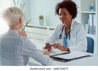 Eine Ärztin sitzt in ihrem Büro und untersucht ältere weibliche Patientin