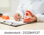  A female doctor sits at a table in a hospital, discussing dental issues like wisdom teeth, cavities, dentures,missing teeth, and cracked teeth, explaining the causes and treatment of dental caries.