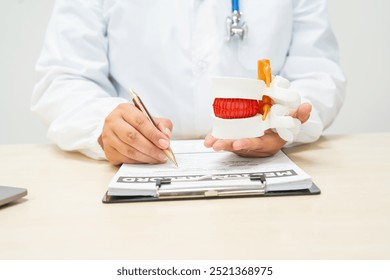 A female doctor sits at a table in a hospital, discussing spine conditions like scoliosis,lumbar disc herniation, degenerative spine disease,and spinal fractures,highlighting risks such as paralysis - Powered by Shutterstock