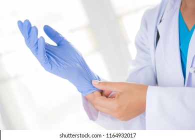 Female doctor with a stethoscope on one shoulder putting on sterile gloves. Healthcare And Medical concept. - Powered by Shutterstock