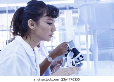 female doctor student examining and analysis virus test sample on microscope. young biotechnology specialist working in lab. medical science laboratory hospital. - Shutterstock ID 2364776355