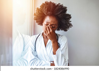 Female doctor suffering from a serious headache while working inside a hospital. She's been under a lot of stress lately. Conceptual of healthcare worker woman having negative feelings. - Powered by Shutterstock