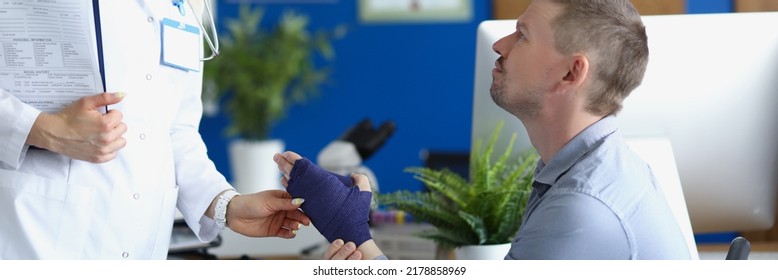 Female Doctor Support Male Patient With Broken Wrist In Bandage