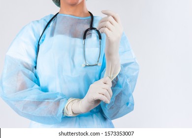 Female doctor surgeon preparing for the surgical operation, she is wearing gloves and scrubs, healthcare and preparation concept. Young doctor putting on rubber gloves in clinic - Powered by Shutterstock