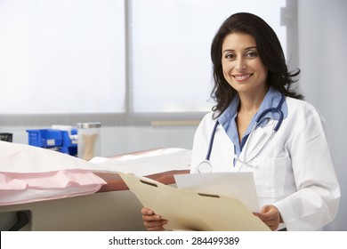 Female Doctor In Surgery Reading Patient Notes