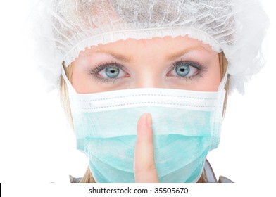 Female doctor with surgical mask and hair net showing the audience to be quiet, copyspace available