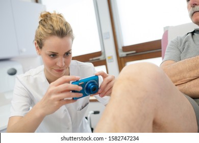 Female Doctor Taking A Picture Of An Injured Knee