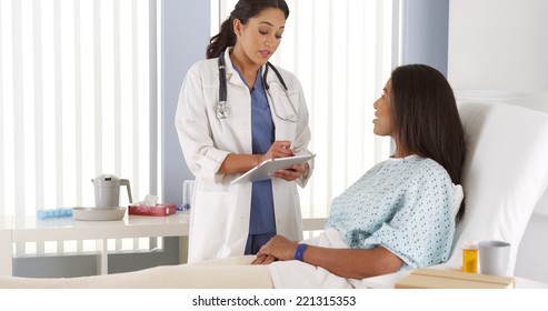 Female Doctor Talking To African American Patient In Hospital Bed