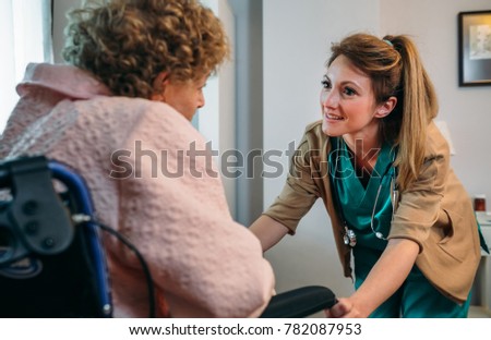 Female doctor talking to elderly patient in wheelchair