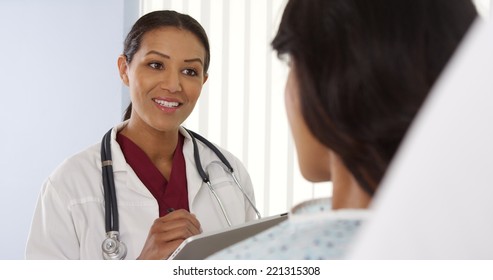 Female Doctor Talking To Hispanic Patient With Tablet Computer