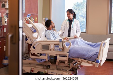 Female Doctor Talking To Male Patient In Hospital Bed