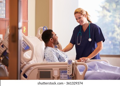 Female Doctor Talking To Male Patient In Hospital Bed