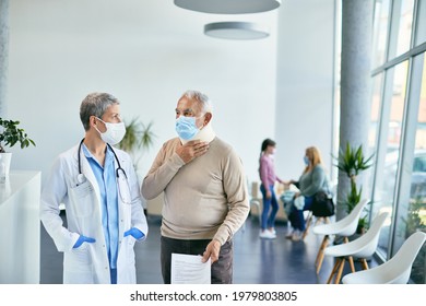 Female Doctor Talking To Senior Patient Who Is Wearing Neck Brace After Medical Exam At The Hospital. They Are Wearing Face Masks Due To Coronavirus Pandemic. 