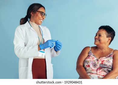 Female Doctor Talking With Senior Woman While Preparing Injection. Healthcare Professional With Elderly Patient In Clinic.