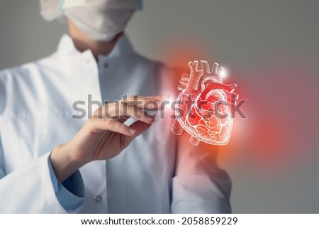 Female doctor touchstone virtual Heart in hand. Blurred photo, handrawn human organ, highlighted red as symbol of disease. Healthcare hospital service concept stock photo
